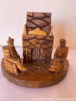 Front view of carved wood diorama showing couple and fireplace