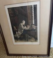 Angled view of framed print leaning against carpeted floor