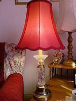 Lamp lit with red fabric shade on wooden side table