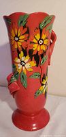 Front view showing hand-painted yellow/orange flowers on red vase