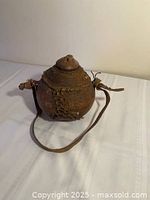 Front angled view showing container shape, stitching, stopper, strap