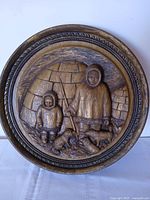 front view of circular carved plaque showing Inuit scene