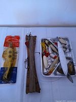 Group shot of packaged Believer lure, wooden handline board, foil tray of loose lures