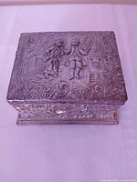 Front and top view of silver-plated box showing repoussé design and hinged lid