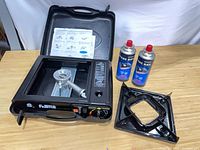 Stove in open case with accessories and two fuel cans