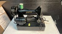 Left side view of black Spartan sewing machine on base with motor and cords visible