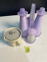 Tupperware condiment set showing two tall cone dispensers, two small shakers, mixing cup with lid, and funnel stand