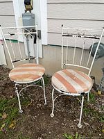 Two white metal chairs with striped seats placed outdoors