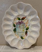 Front view of oval ceramic platter showing twelve egg wells and central asparagus painting
