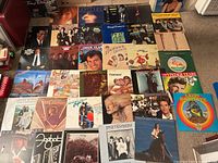 Wide view of approx. 35 album covers laid out on floor