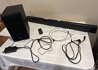 Soundbar, subwoofer, remote, cables laid out on table