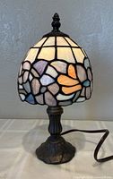 Full view of lamp lit showing stained glass shade and metal base