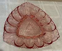 Full view of triangular pink Depression glass deviled egg dish