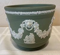Front view of Wedgwood sage green jasperware jardiniere showing white relief decoration