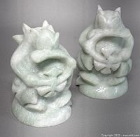 Front view of both pale green stone squirrel figurines