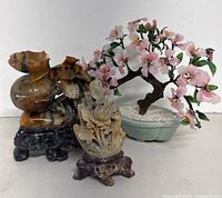 group shot of both soapstone carvings and bonsai tree