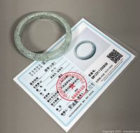 Jade bangle with first laminated certificate showing measurements and red stamp