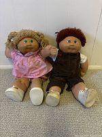 Both Cabbage Patch dolls seated against wall, full view