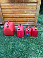Four red plastic jerry cans lined up by size