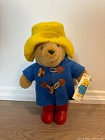 Full view of plush Paddington Bear wearing coat, hat, boots
