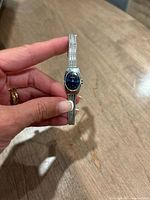 Front view showing blue dial, silver case, mesh bracelet