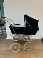Left side view of navy corduroy dolls pram showing metal frame and wheels