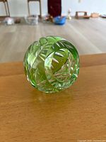 Front view of spherical green glass ashtray showing cut leaf patterns and side opening