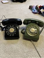 Black and green rotary dial desk telephones side by side