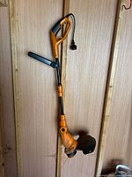 Full view of Worx corded string trimmer hanging on wall showing overall condition