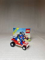 Front view of assembled buggy, minifigure seated, instruction booklet visible