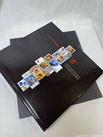 Hardcover yearbook stacked on slipcase showing glossy cover with stamp images