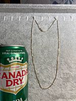 Full view of gold chain on towel beside soda can for scale