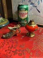 Front view of miniature shoe and lamp with can for scale