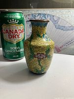 Front view of cloisonné bud vase next to soda can for scale
