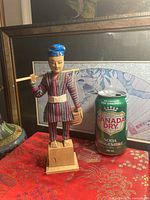 Front view of carved wood figure beside soda can for scale
