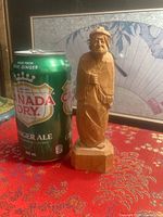 Front view of wooden figurine beside soda can for scale