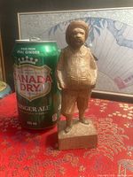 Full view of carved figurine beside 355 ml can for scale