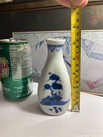 Full view of sake bottle beside soda can and tape for scale