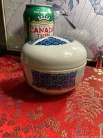 Bowl with lid closed beside soda can showing size and blue exterior pattern