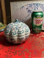 Covered scalloped porcelain dish beside soda can for scale