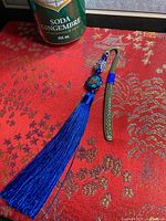 Bookmark laid on red fabric showing tassel, beads, and metal hook