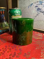 Front and side view of glossy green ceramic vase beside soda can for scale