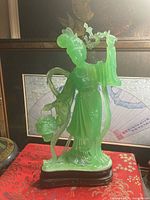 Front view of translucent green resin Chinese lady figurine on black stand