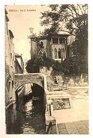 Front view of postcard showing canal, bridge, and buildings