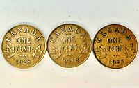 Reverse side of three 1928 Canada one cent coins showing date and maple leaves