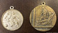 Front view of both medals showing soccer scenes and eyelets