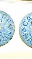Obverse sides of both blue fibre Canadian meat ration tokens showing text and central holes