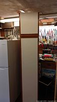 Full side view of tall cabinet beside fridge, showing height and wood veneer side