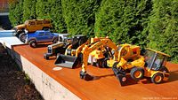All seven toy vehicles lined on wood surface outdoors