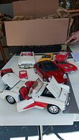 Overview showing six model cars on table including white/red convertible, red coupe, yellow targa, two white convertibles